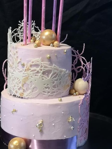Pink ganache cake with pink chocolate lace and swirled chocolate cake pops and gold balls