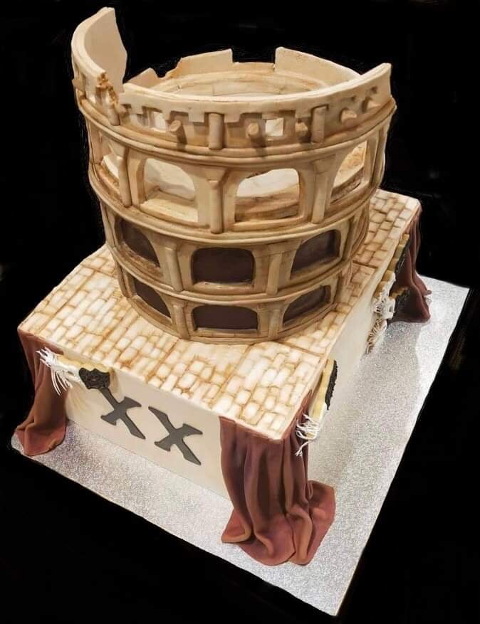 Coliseum and theatre cake combining two themes in two layers, with cookie masks and fondant curtains and fondant roman coliseum